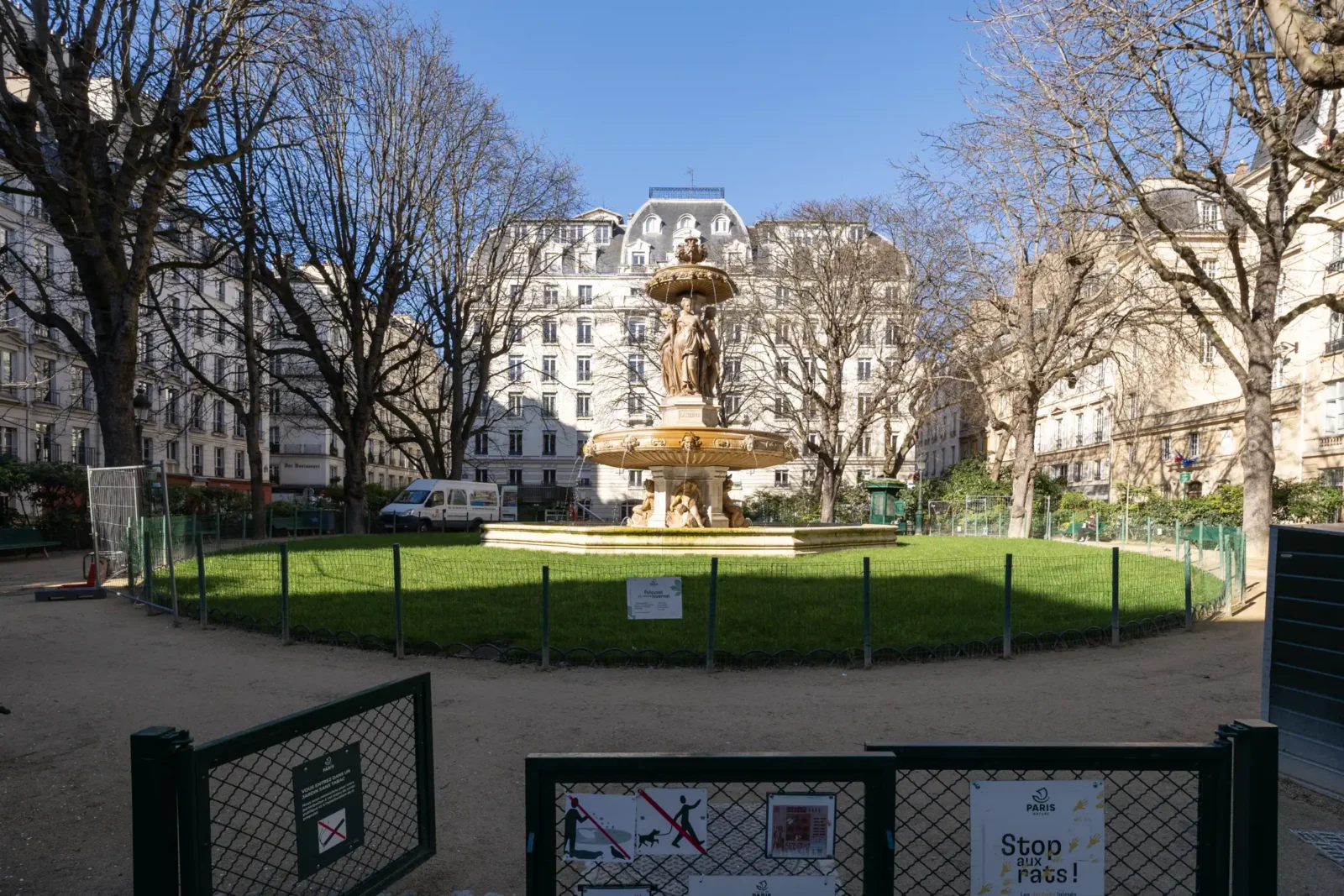 La fontaine Louvois se dresse au centre d'un jardin parisien entouré de grilles signalétiques.