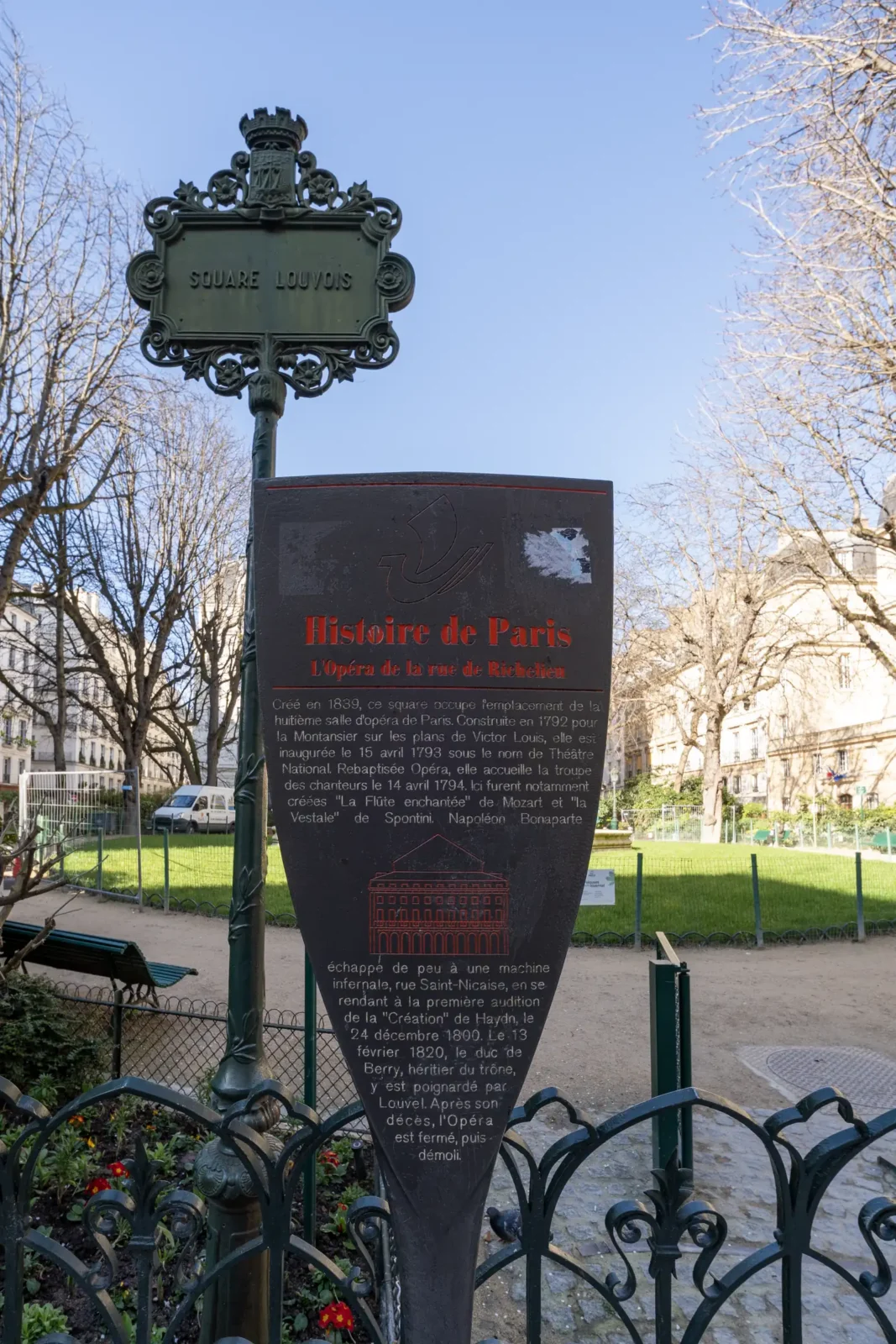 Un panneau informatif sur l'histoire de l'Opéra dans le verdoyant square Louvois parisien.