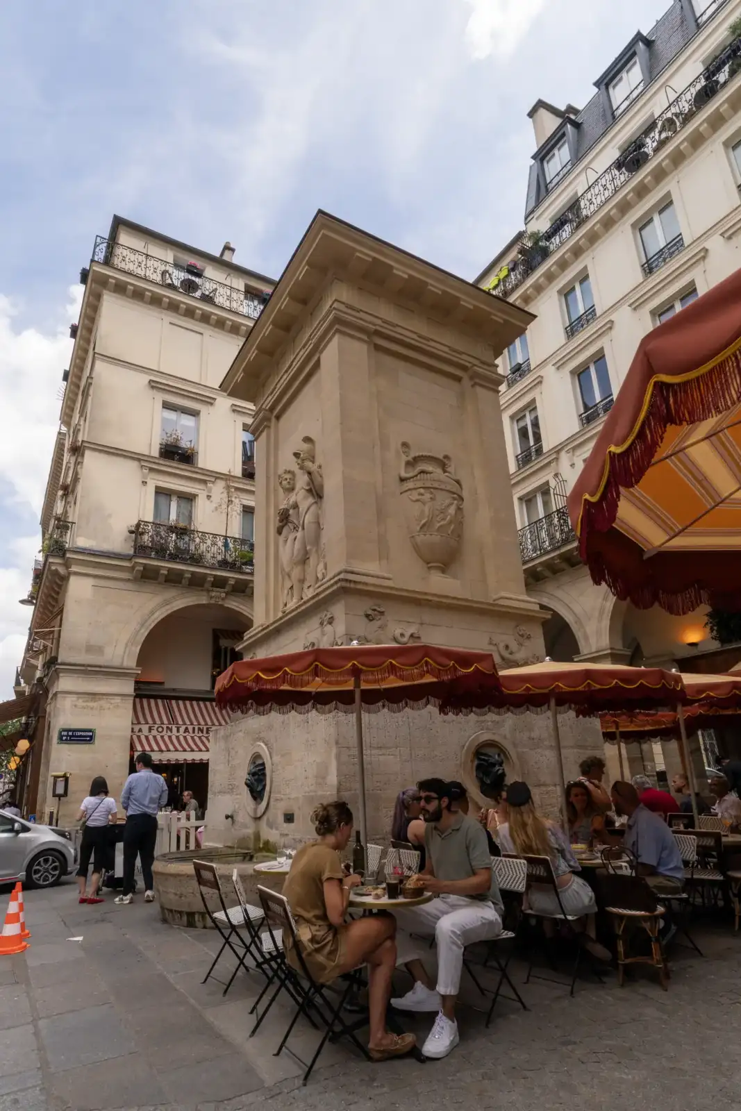 Des clients attablés en terrasse autour de la fontaine sculptée de Mars à Paris.