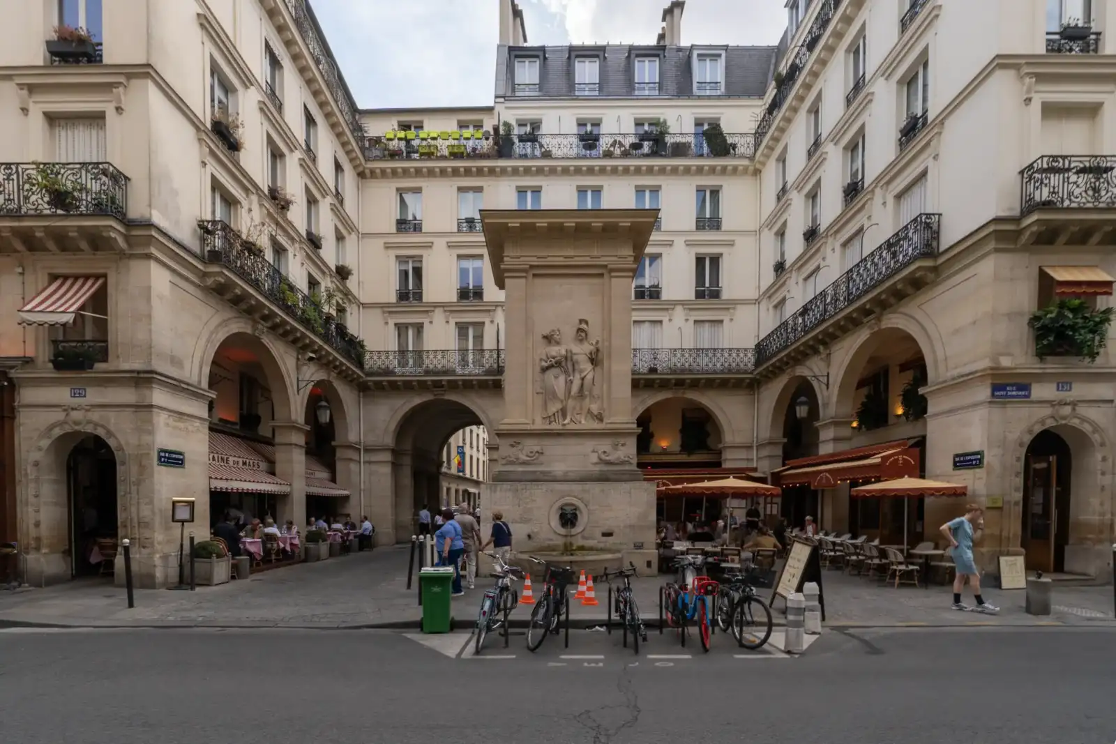 La fontaine de Mars monumentale au centre d une place parisienne entourée de beaux immeubles anciens.