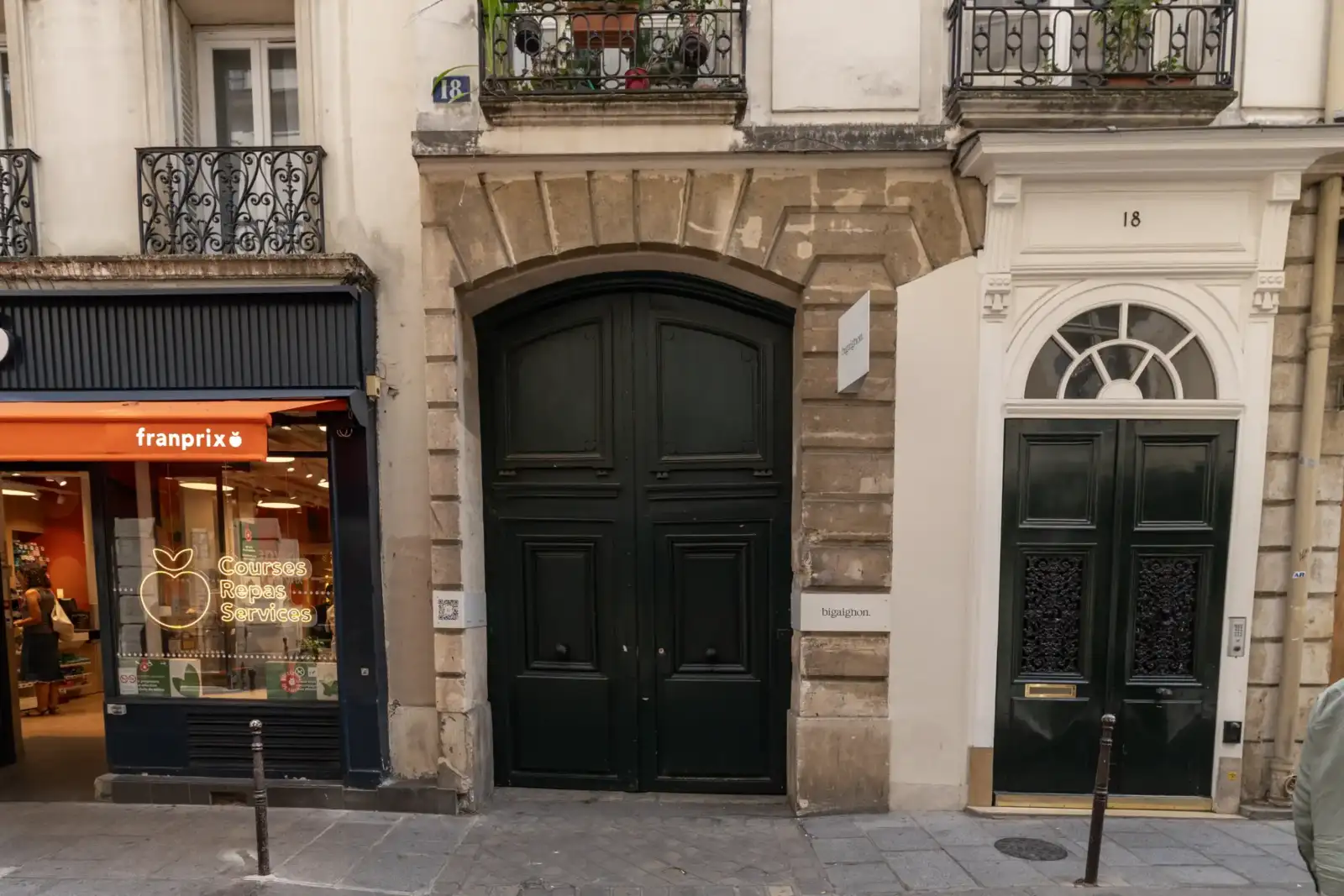 Une grande porte cochère noire de la galerie Bigaignon sur une façade parisienne.