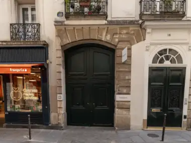 Une grande porte cochère noire de la galerie Bigaignon sur une façade parisienne.