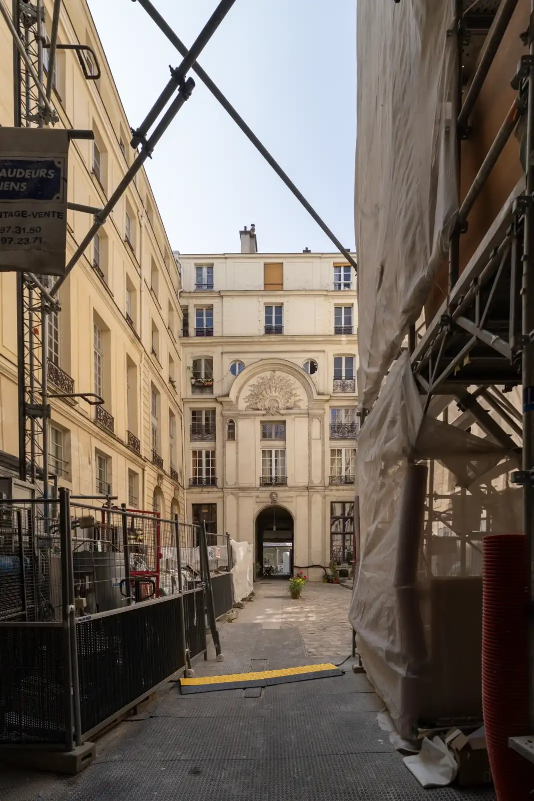 Vue en contre-plongée d une cour pavée parisienne encadrée par des échafaudages de chantier.