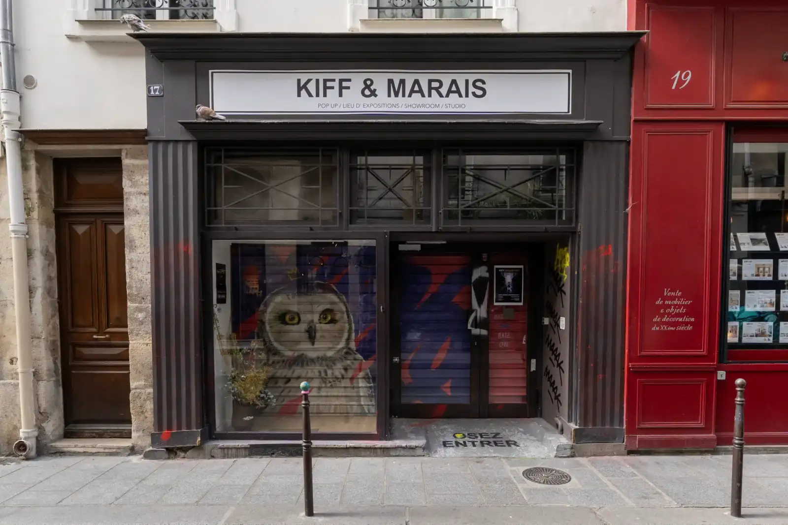 La devanture sombre de la galerie Kiff et Marais arbore une grande enseigne blanche.