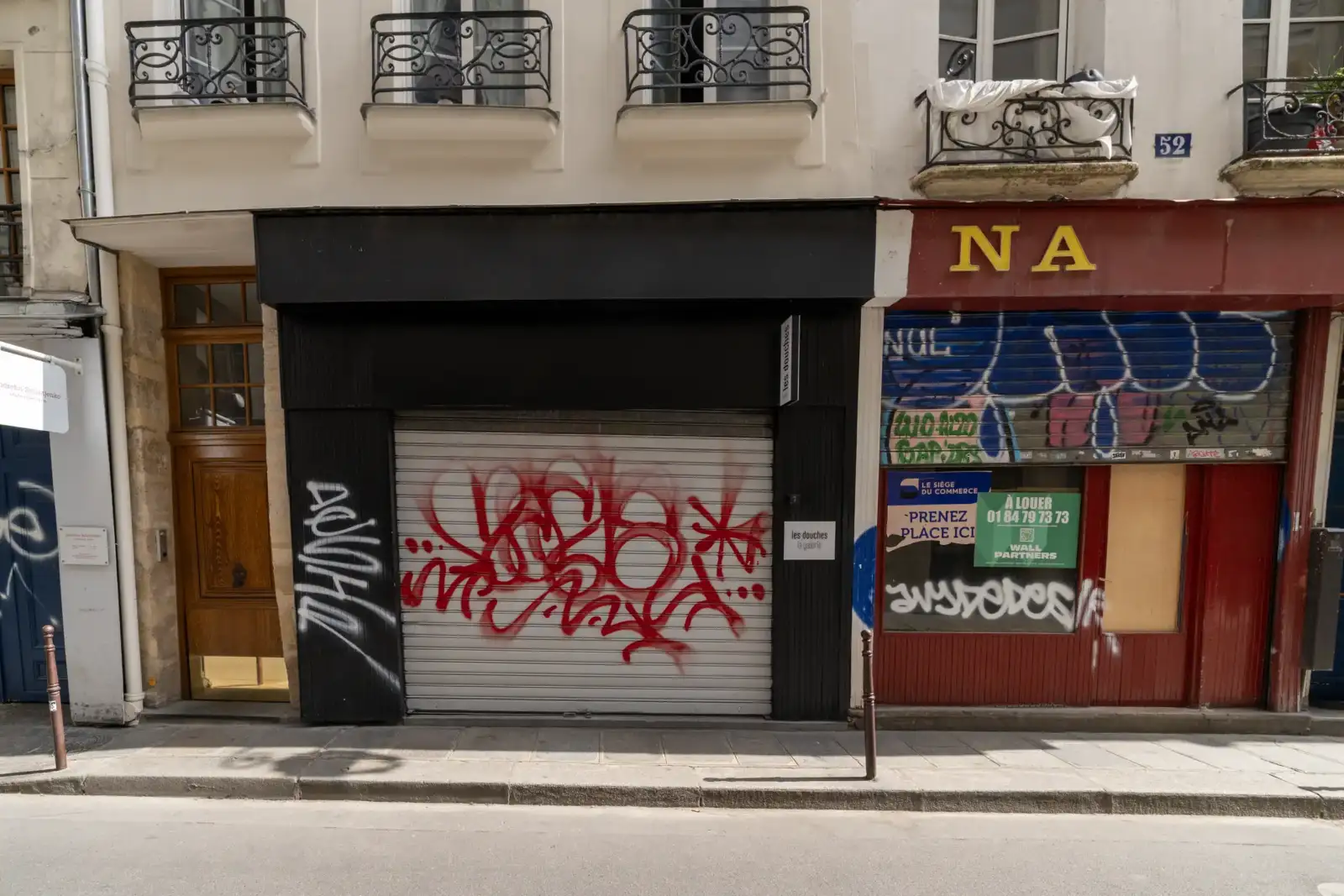Entrée de la galerie d art les douches fermée par un rideau métallique tagué.