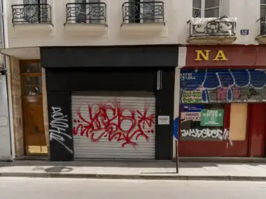 Entrée de la galerie d art les douches fermée par un rideau métallique tagué.