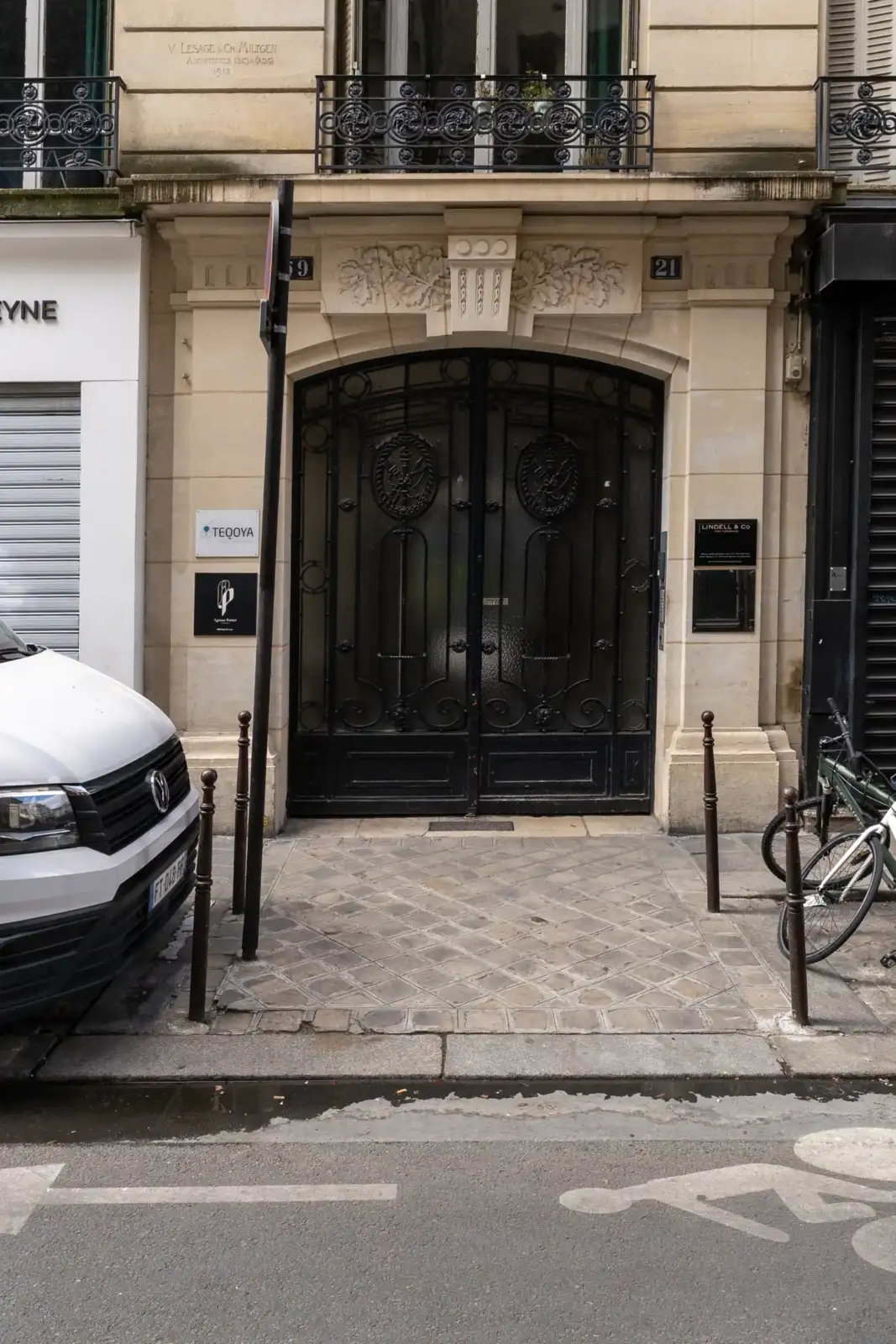 Une entrée élégante d'un immeuble parisien avec de grandes portes en fer forgé noir.