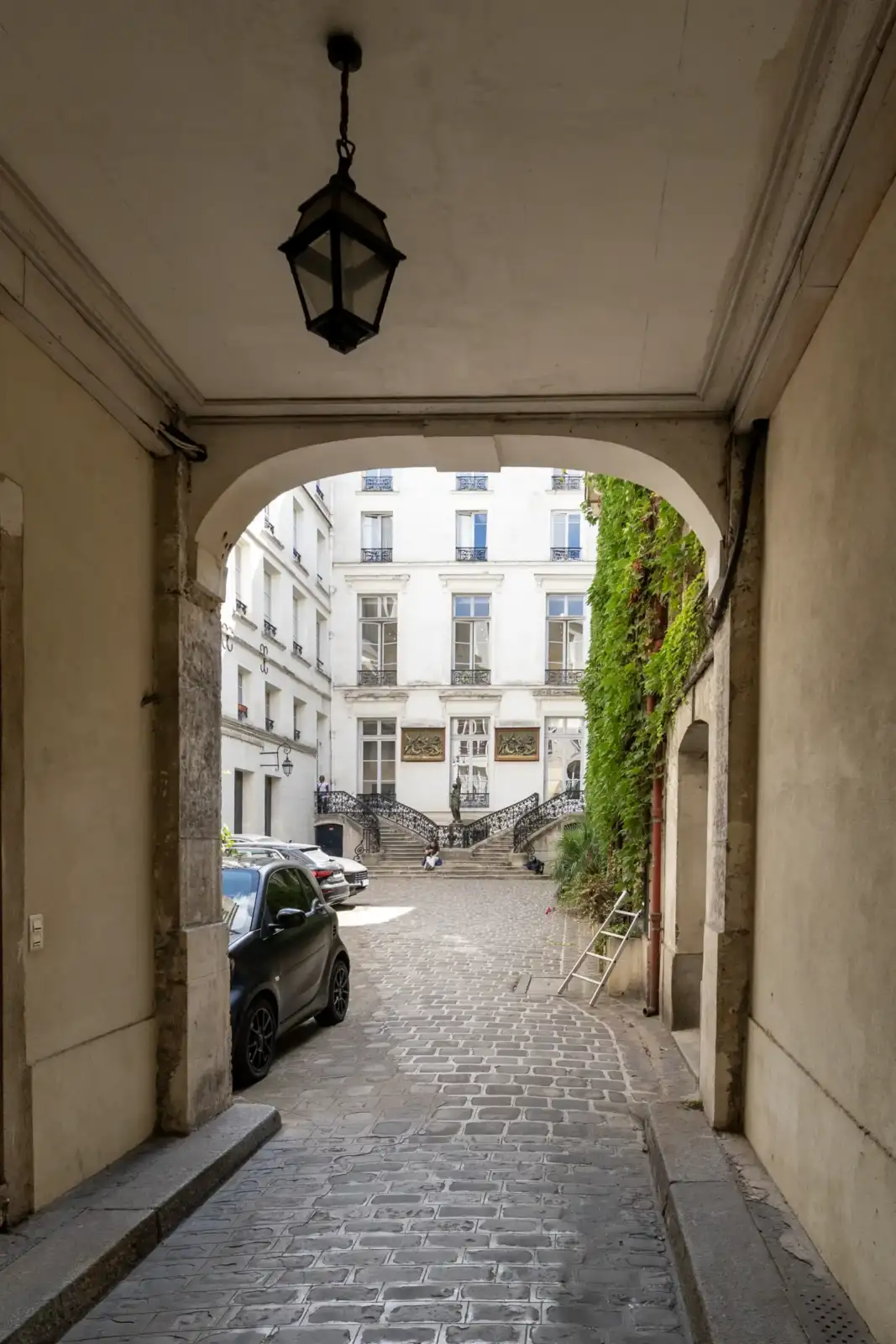 Une vue de la galerie perrotin à travers une arche pavée.