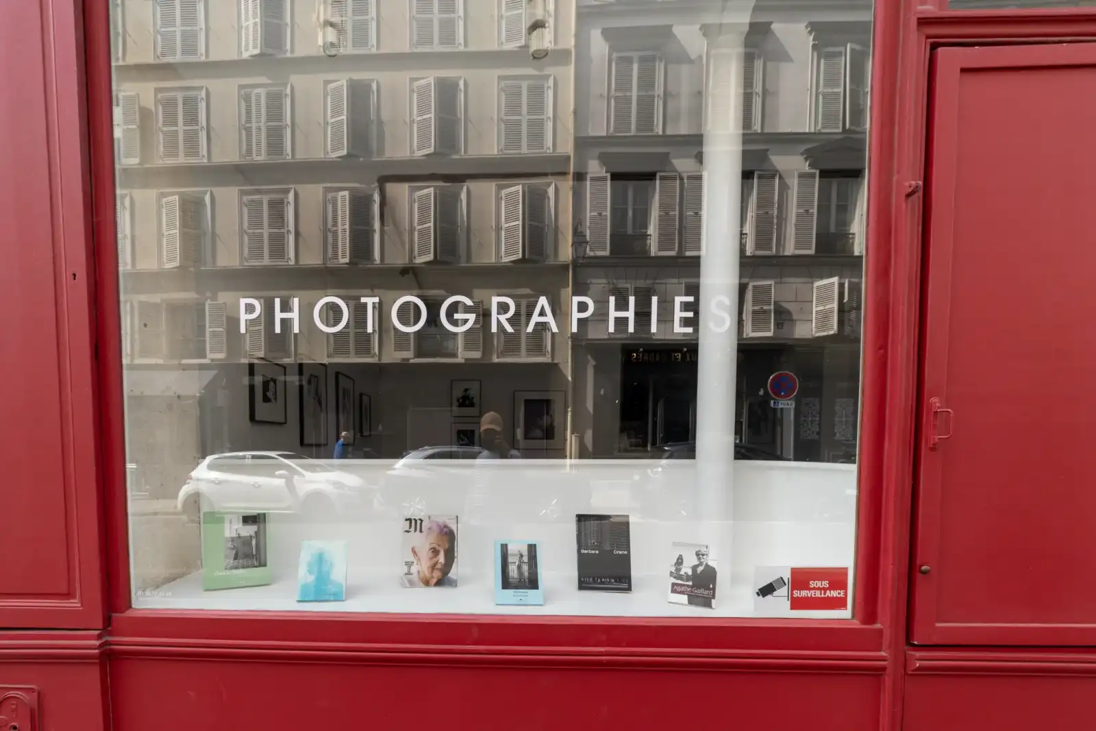 Vitrine rouge affichant le mot photographies et exposant des livres d art à Paris.