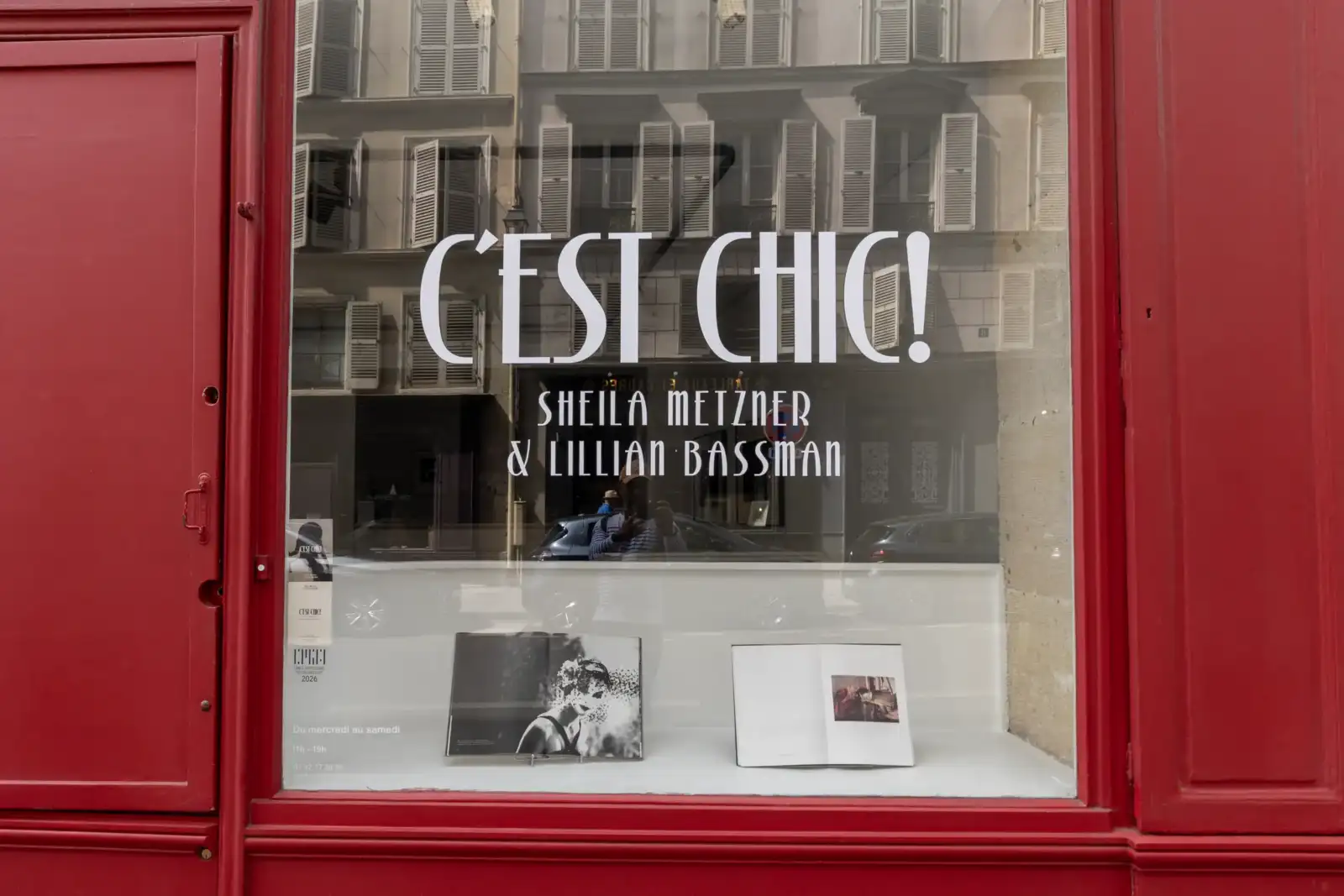 Vitrine parisienne rouge affichant l'inscription C est chic et deux livres ouverts.