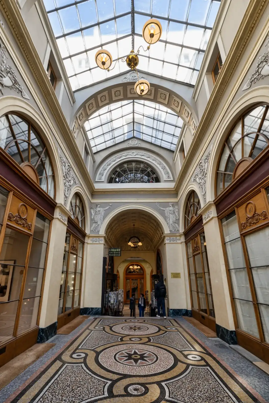 La Galerie Vivienne présente une verrière lumineuse et un sol en mosaïque très détaillé.