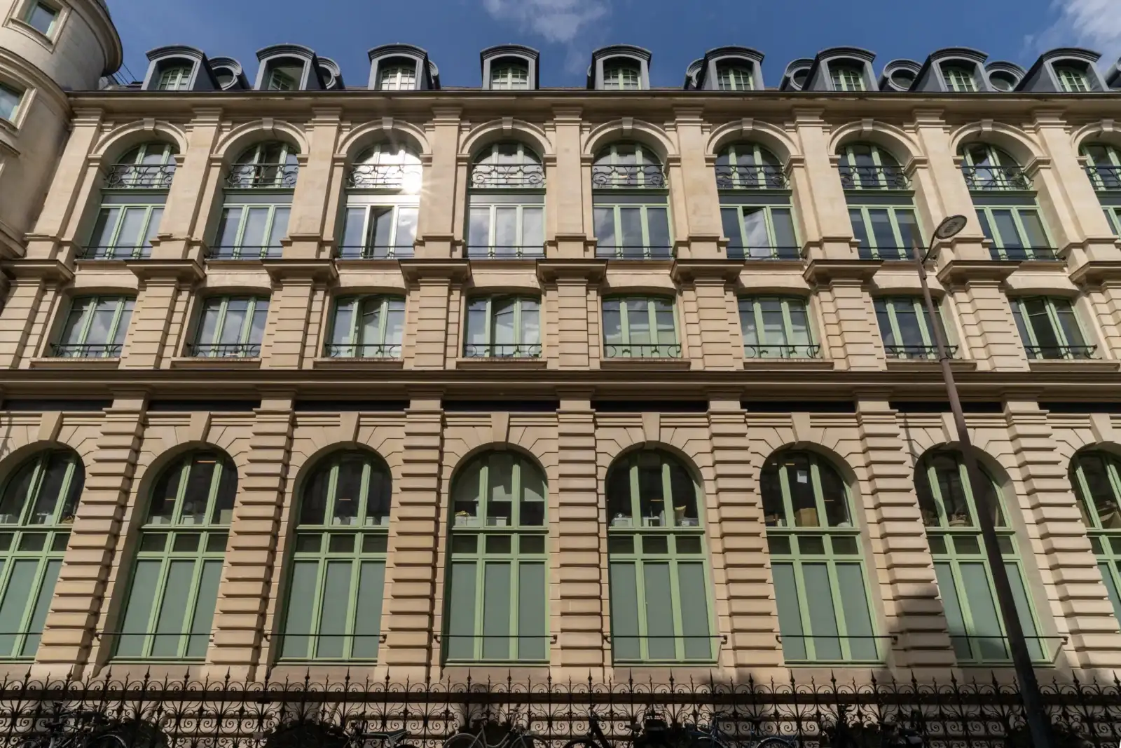 Façade classique aux grandes fenêtres vertes du grand magasin parisien Le Bon Marché.