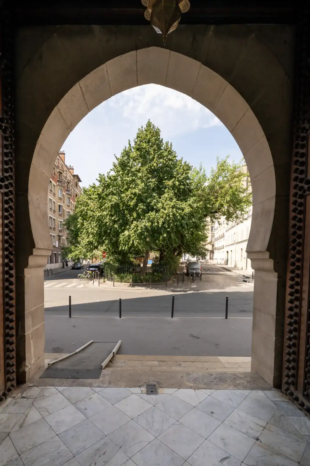 Vue encadrée depuis l entree de la Grande Mosquee montrant une place parisienne verdoyante.