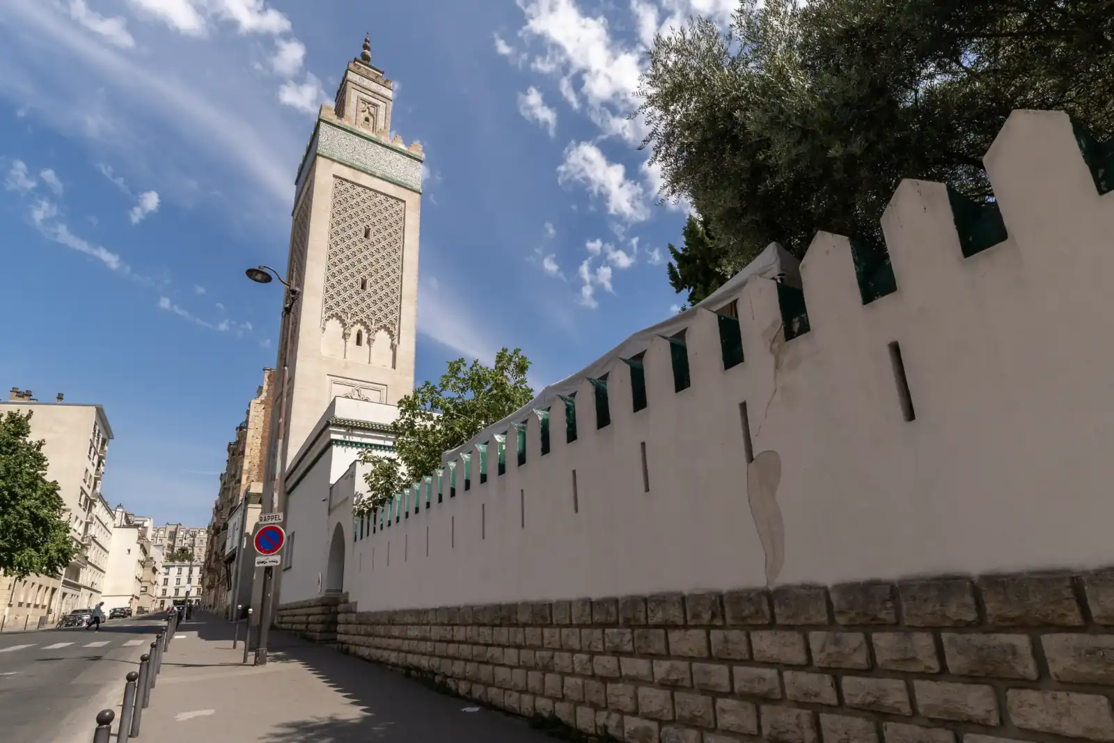 Vue de rue de la grande mosquée de Paris sous un ciel bleu nuageux.