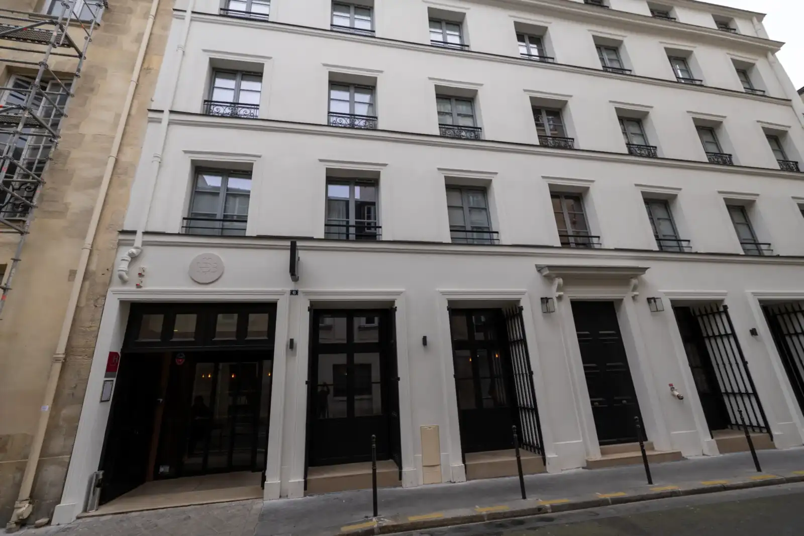 Façade blanche classique de l'hôtel Le Boudoir des Muses dans une rue parisienne.