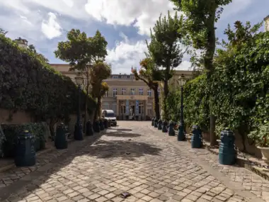 Vue en contre-plongée de la cour pavée de l'hôtel de Monaco avec un magnifique jardin.