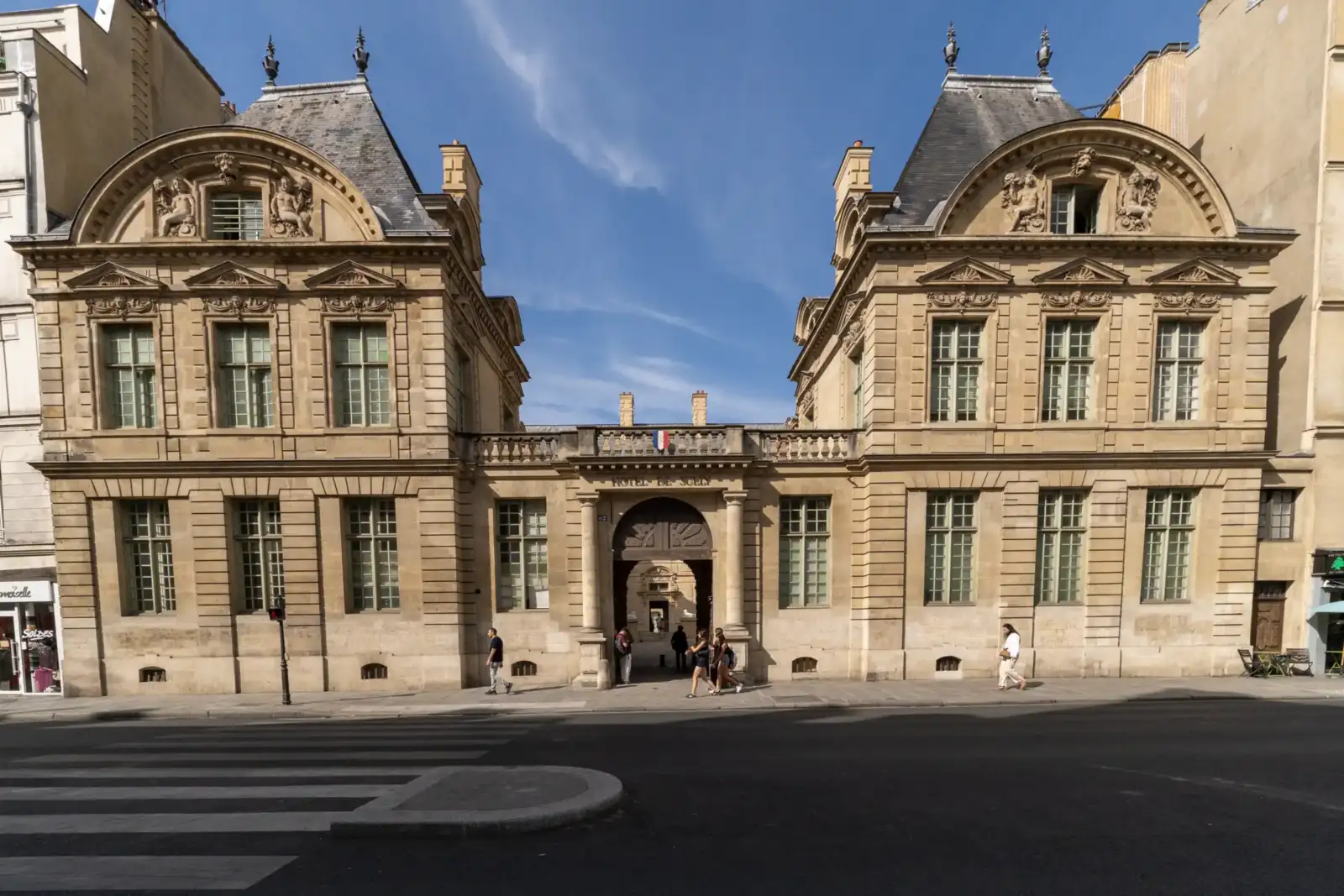 Façade en pierre claire de l'Hôtel de Sully à Paris sous un ciel bleu.