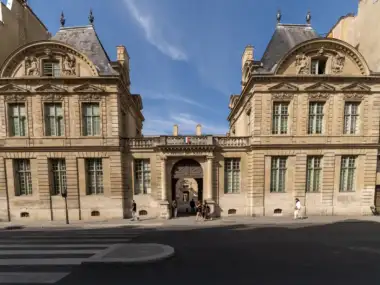 Façade en pierre claire de l'Hôtel de Sully à Paris sous un ciel bleu.