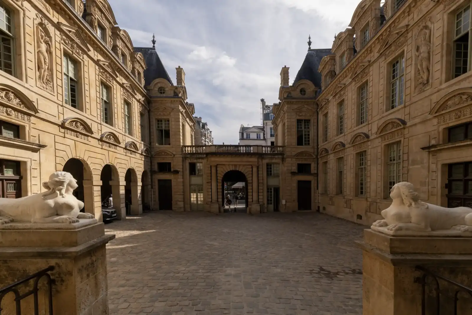 La cour pavée de l'hôtel de Sully montre ses façades sculptées et deux sphinx blancs.