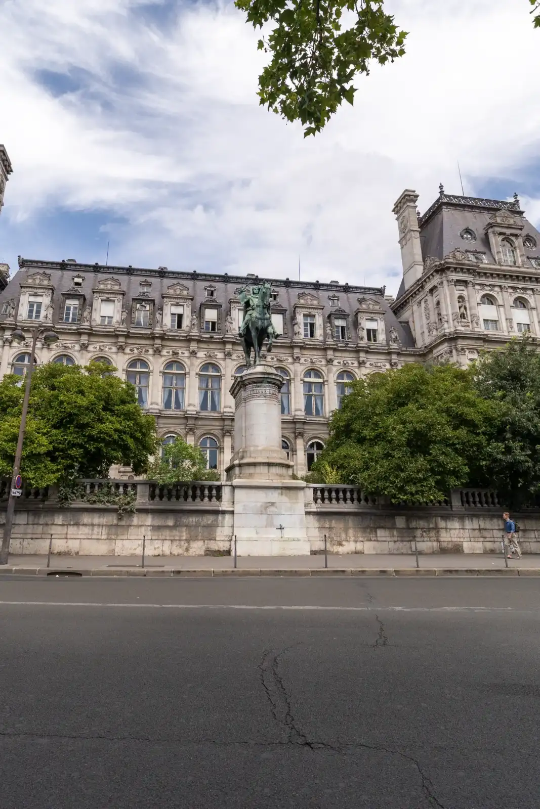 Façade ornée et statue équestre de l'Hôtel de Ville de Paris sous un ciel nuageux.