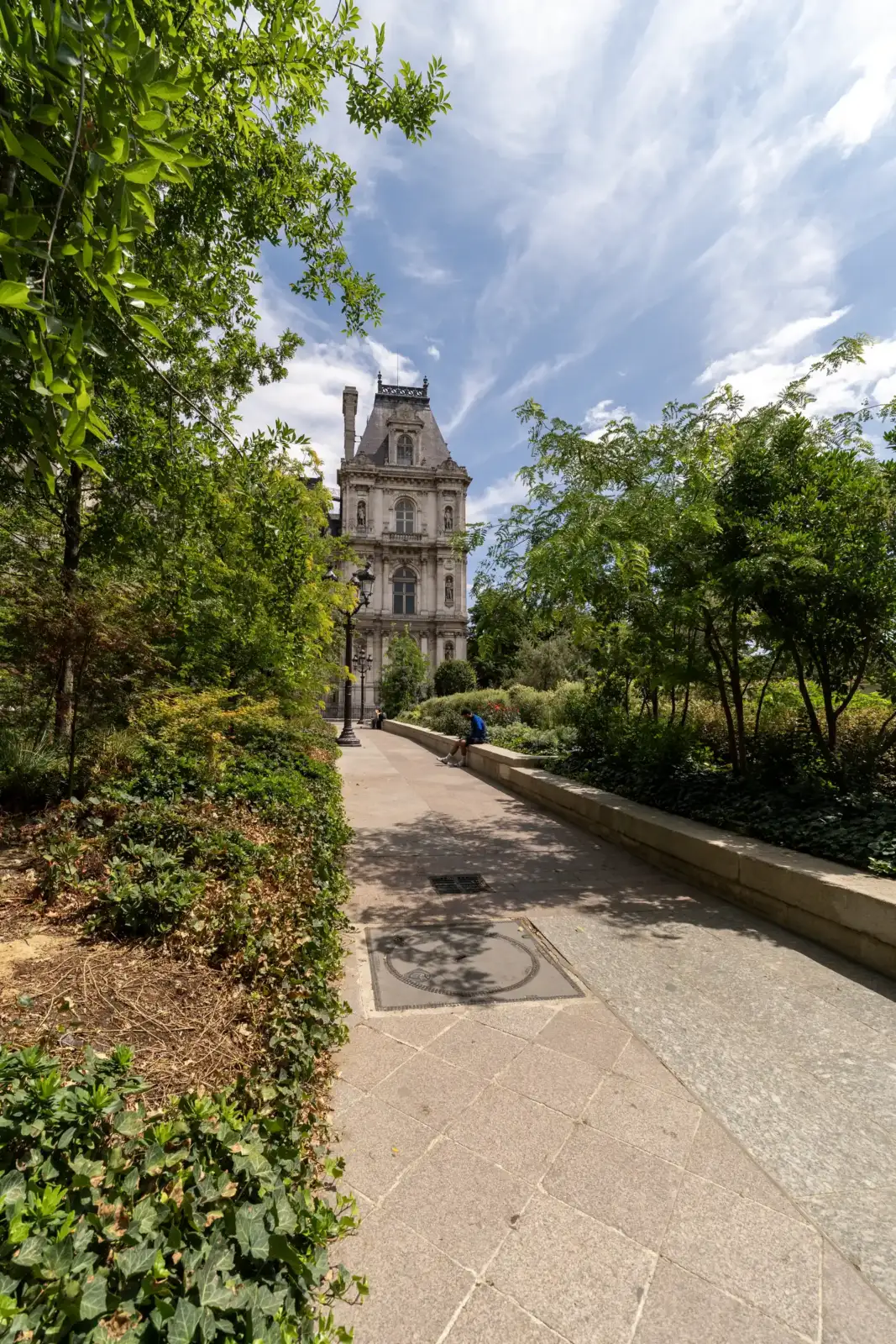 Une allée pavée bordée de verdure mène à la façade de l Hotel de Ville de Paris.