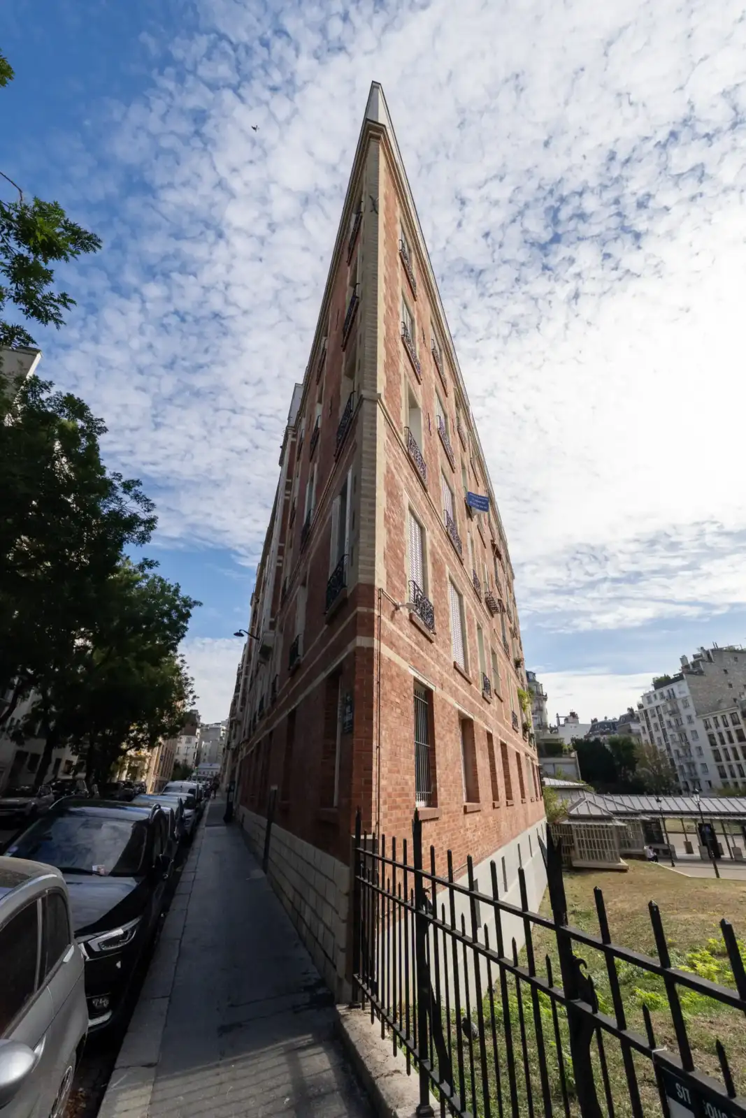 Vue en contre-plongée d'un immeuble extra-plat aux briques rouges à Paris.