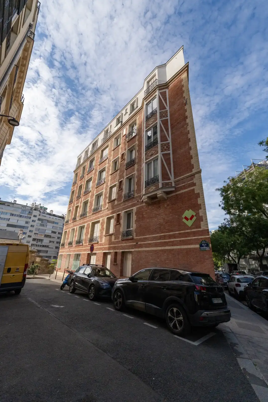 Façade étroite d un immeuble parisien en briques rouges sous un ciel nuageux.