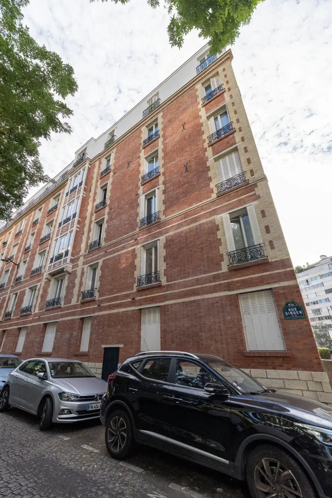 Vue depuis la rue d un immeuble parisien très plat bordé par des voitures