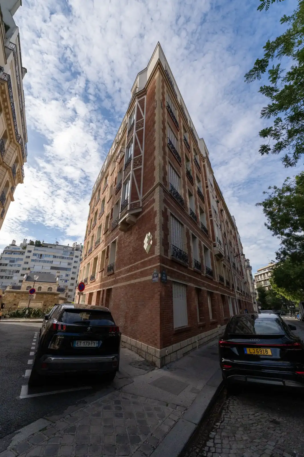 Vue en contre-plongée d un immeuble parisien très fin avec des voitures garées de chaque côté.