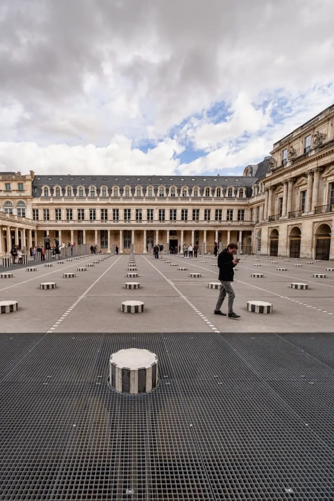 Des personnes marchent parmi les colonnes rayées de Buren dans la cour du Palais-Royal.