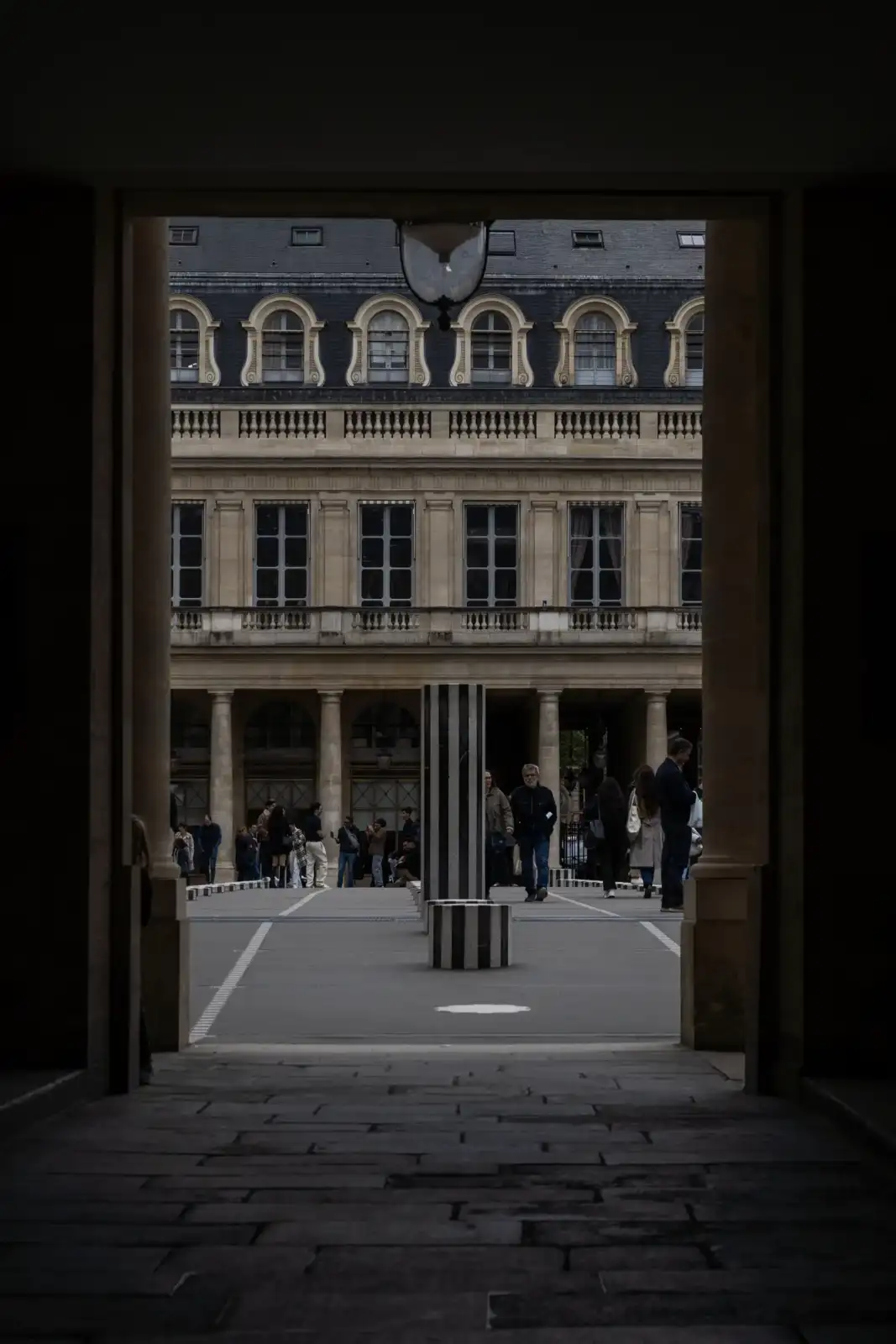Des personnes déambulent parmi les colonnes de Buren rayées dans la cour du Palais-Royal.