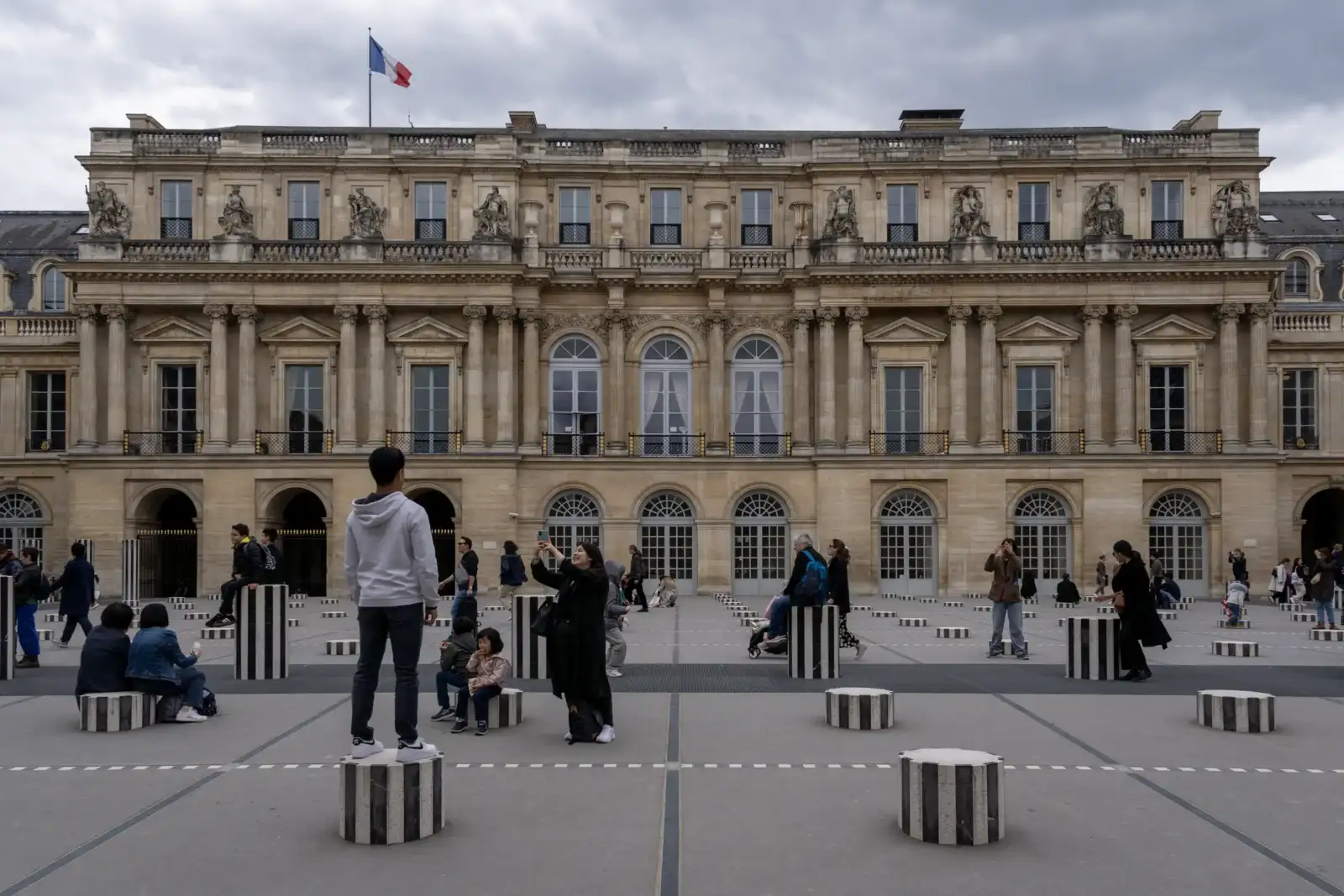 Des visiteurs déambulent parmi les colonnes de Buren devant le Palais Royal à Paris.