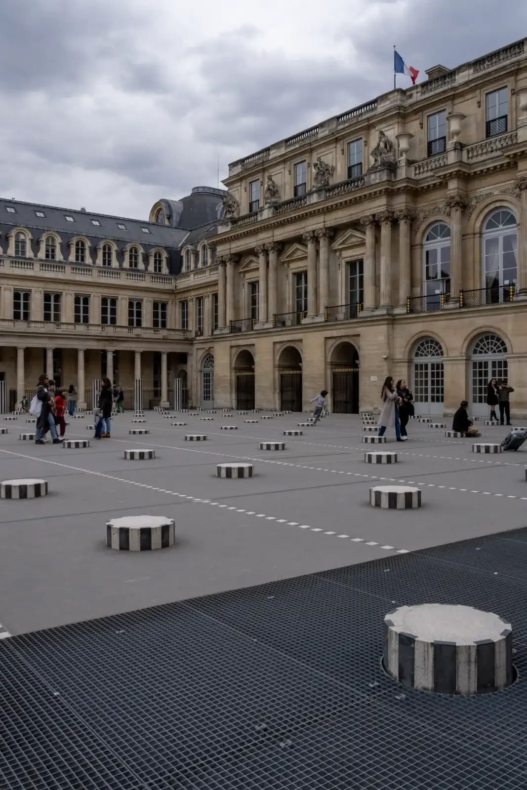 Des visiteurs se promènent parmi les colonnes de Buren dans la cour du Palais-Royal.
