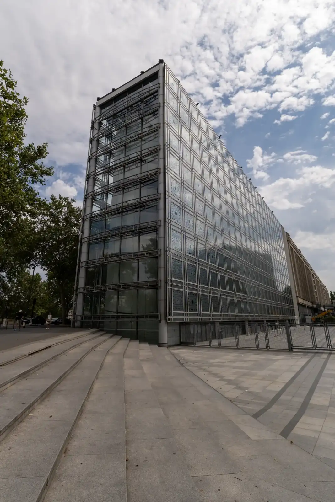 Façade vitrée et moderne de l'Institut du monde arabe sous un ciel nuageux à Paris.