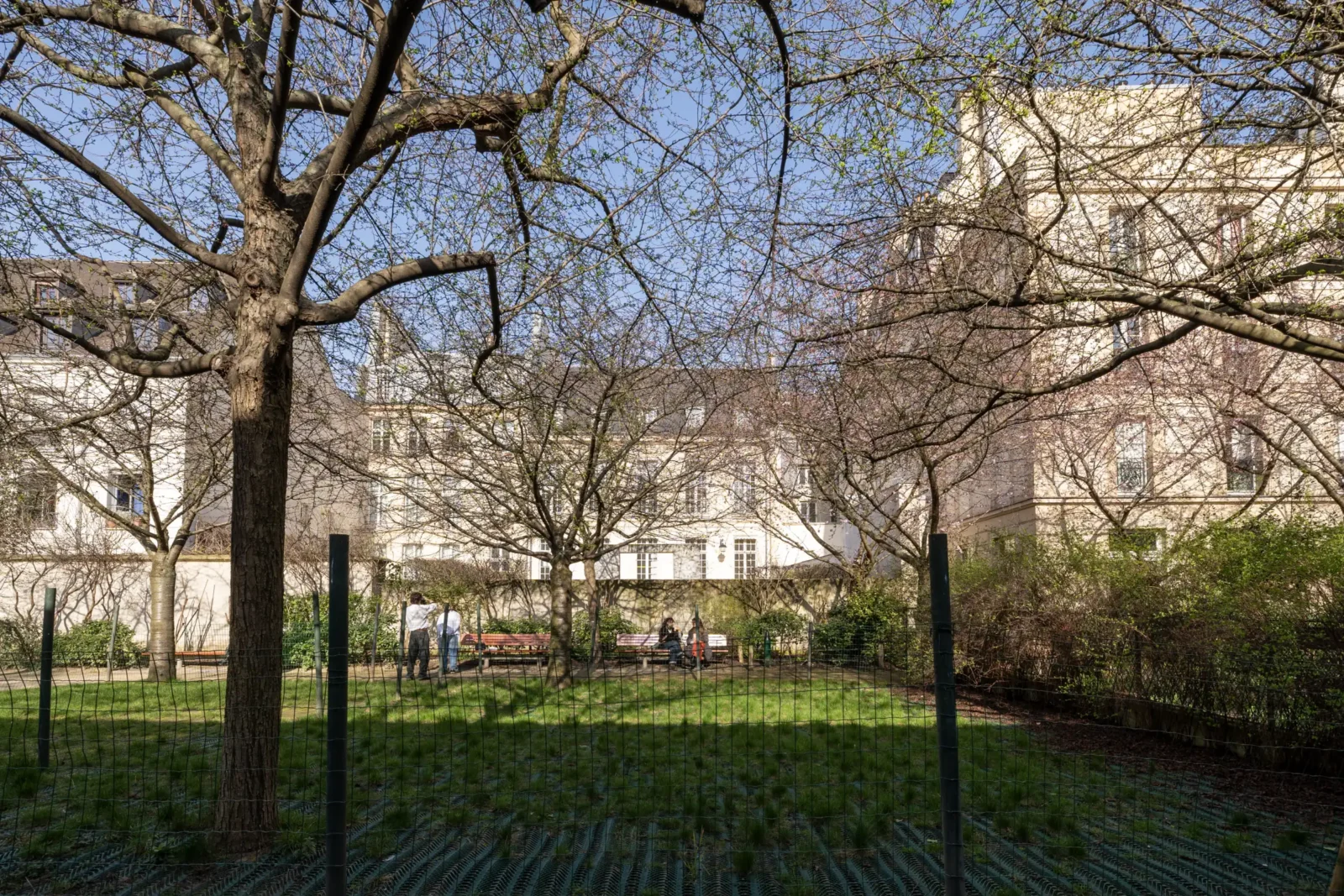 Des personnes se reposent dans le jardin Anne Frank entouré d'arbres au printemps.