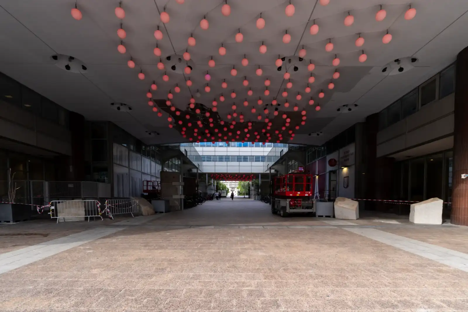 Une allée pavée en contrebas de l'immeuble avec des décorations roses suspendues au plafond.