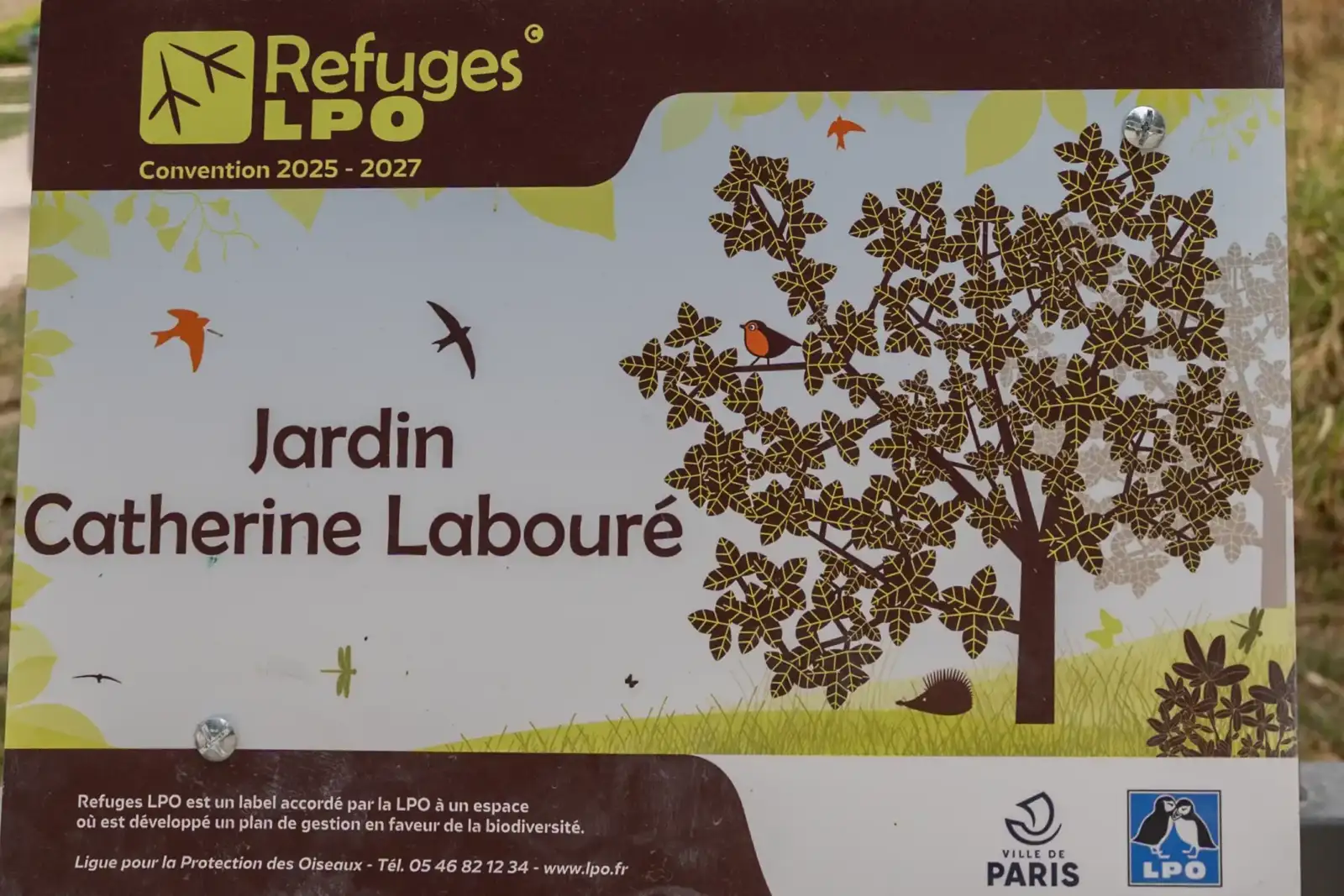 Un panneau d’information du Jardin Catherine Labouré illustre des oiseaux, un hérisson et des arbres.