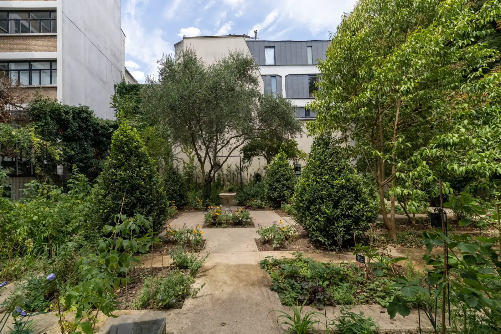 Vue du jardin partagé le Clos des Blancs Manteaux entouré de verdure et d immeubles parisiens.