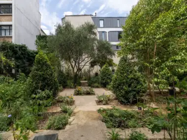 Vue du jardin partagé le Clos des Blancs Manteaux entouré de verdure et d immeubles parisiens.