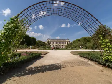 Une grande arche métallique fleurie encadre la superbe façade du Jardin des Plantes à Paris.
