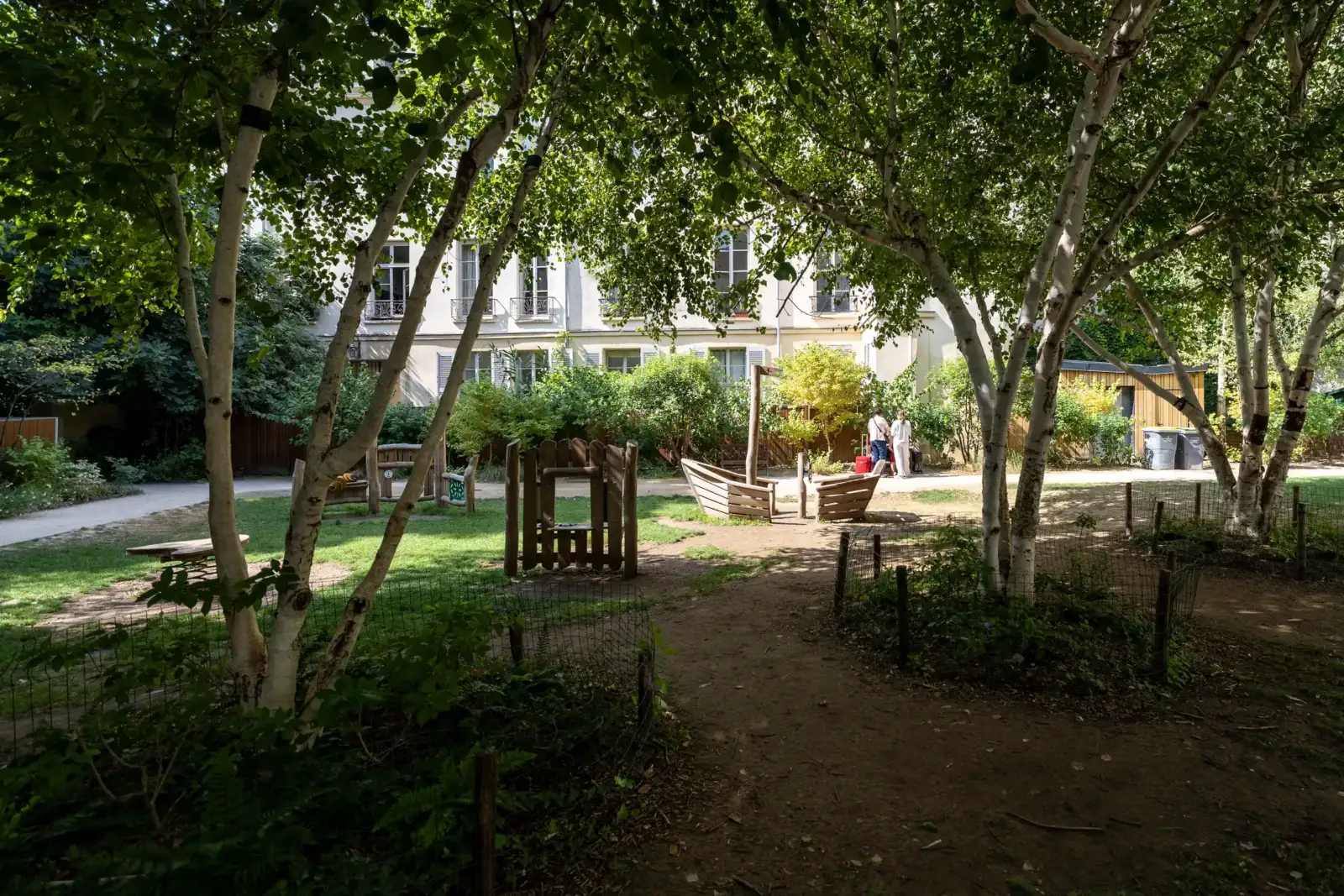 Des bouleaux ombragent une aire de jeux pour enfants dans ce jardin parisien.