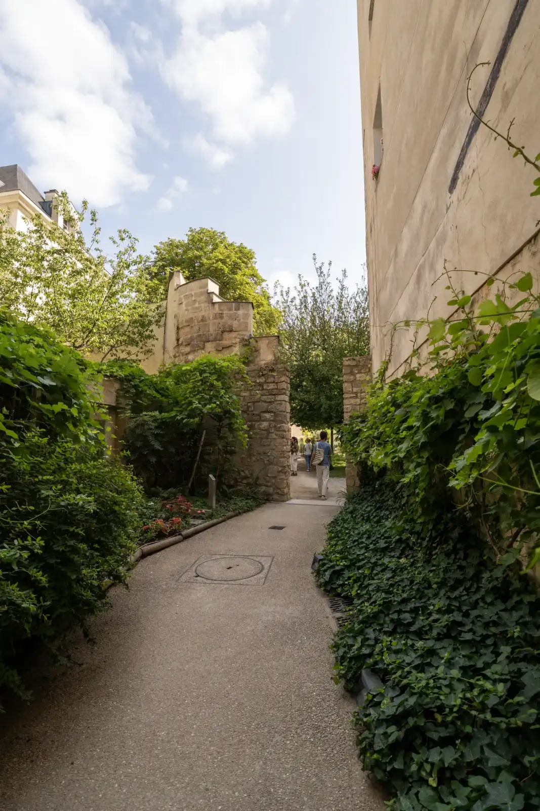 Une allée verdoyante bordée de murs en pierre mène au jardin Joseph Migneret.