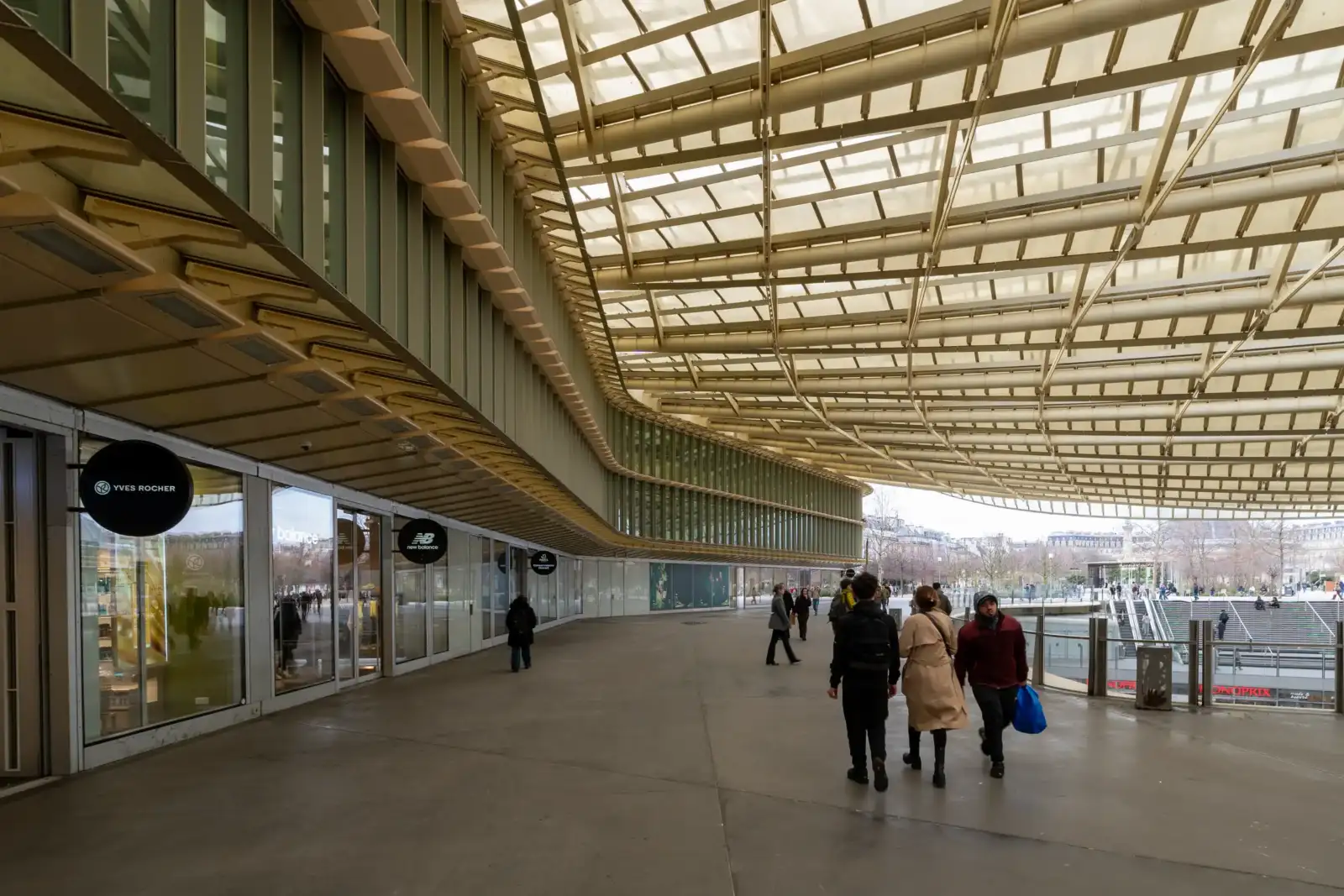 Des passants marchent sous l'immense toit vitré et moderne de la Canopée des Halles.