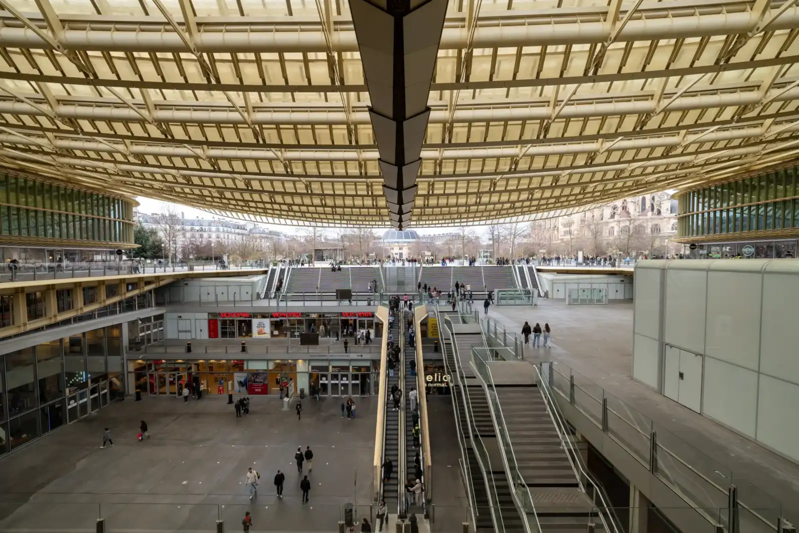 La grande verrière dorée surplombe les escaliers et les passants de la Canopée parisienne.