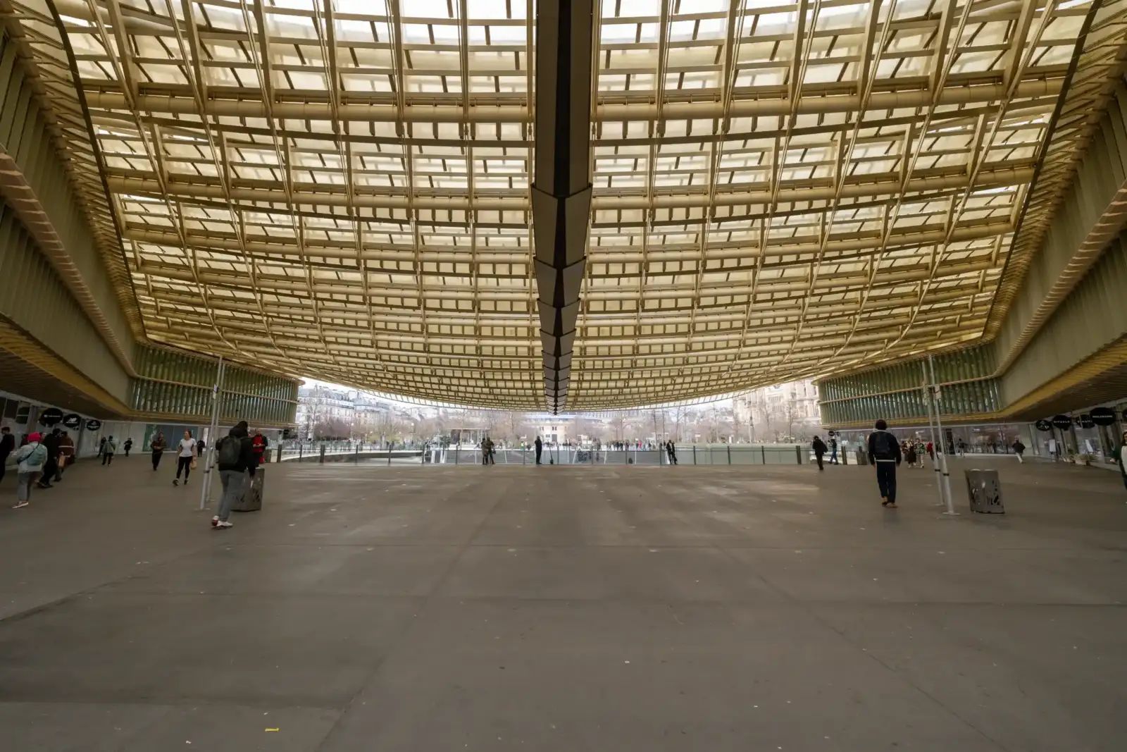 La grande toiture dorée et ondulée couvre une vaste place piétonne aux Halles Paris.