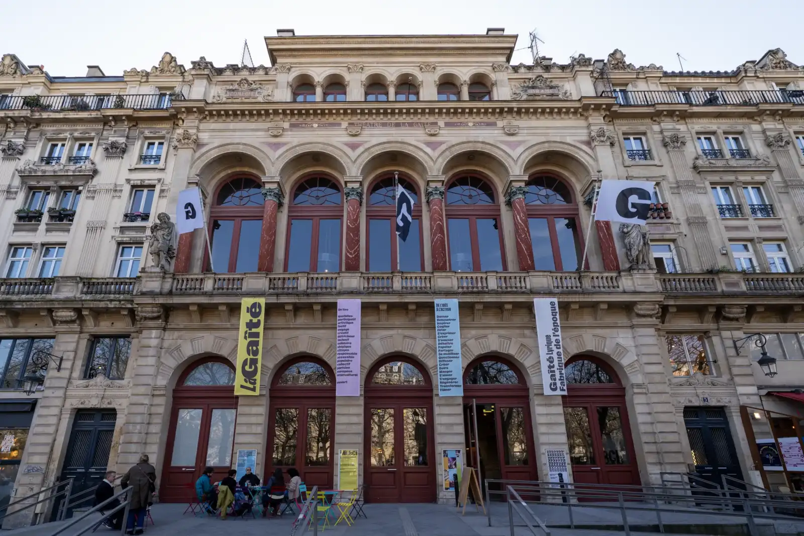 La façade historique de la Gaîté Lyrique avec ses bannières colorées et terrasses extérieures.