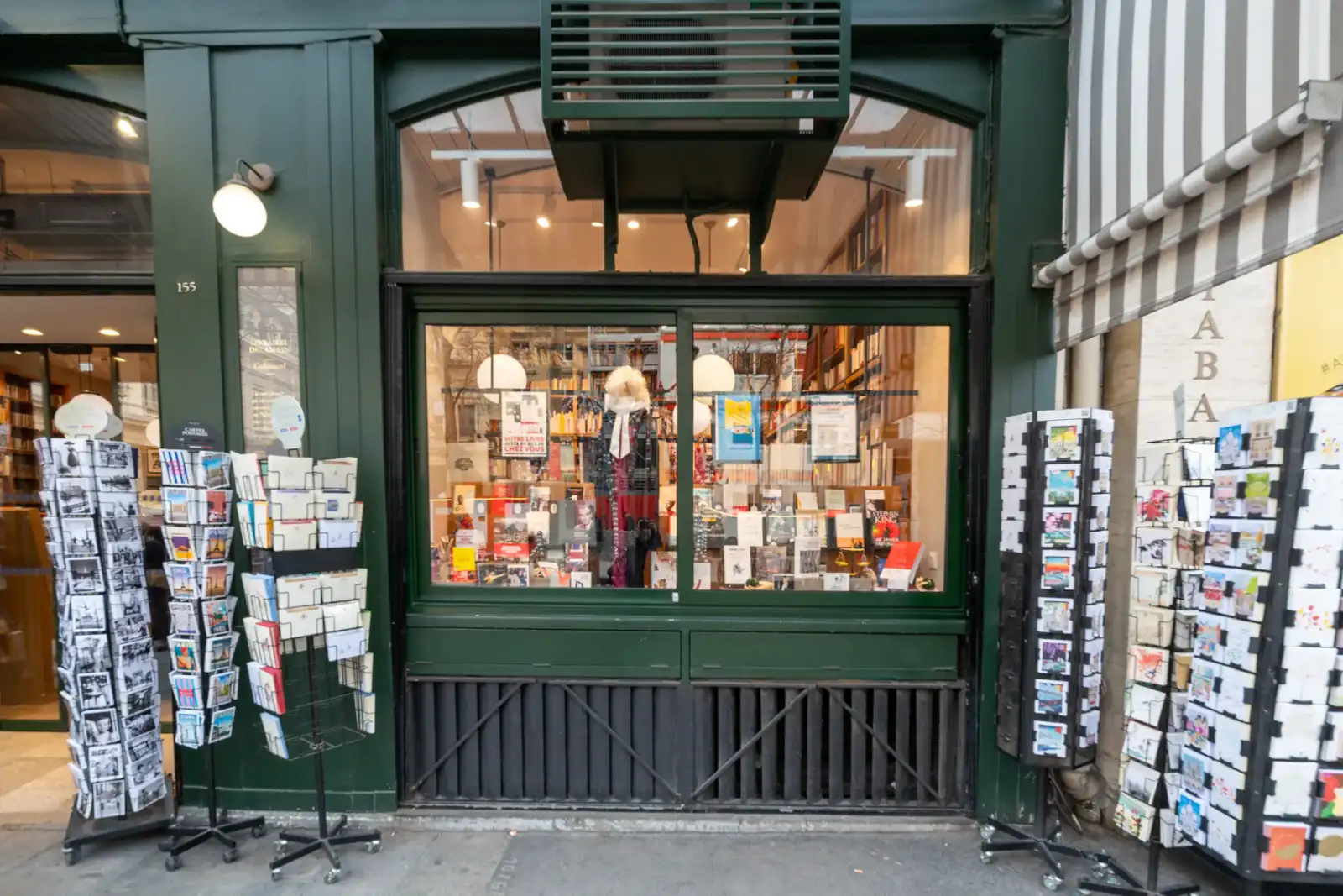 La devanture verte de la librairie Delamain à Paris présente une vitrine remplie de livres.