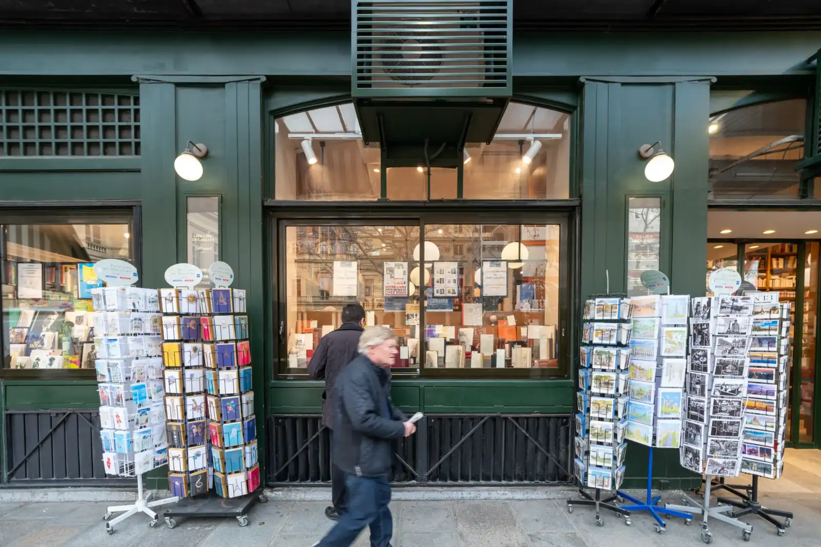 La façade verte de la librairie Delamain avec des présentoirs de cartes postales devant.