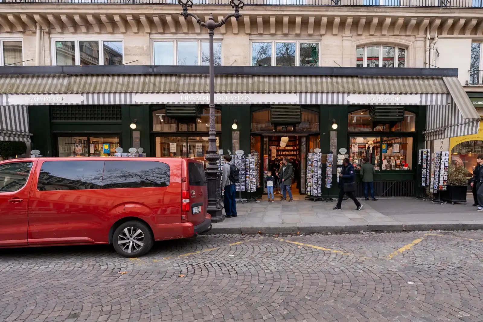 La devanture de la librairie Delamain à Paris avec un van rouge stationné devant.