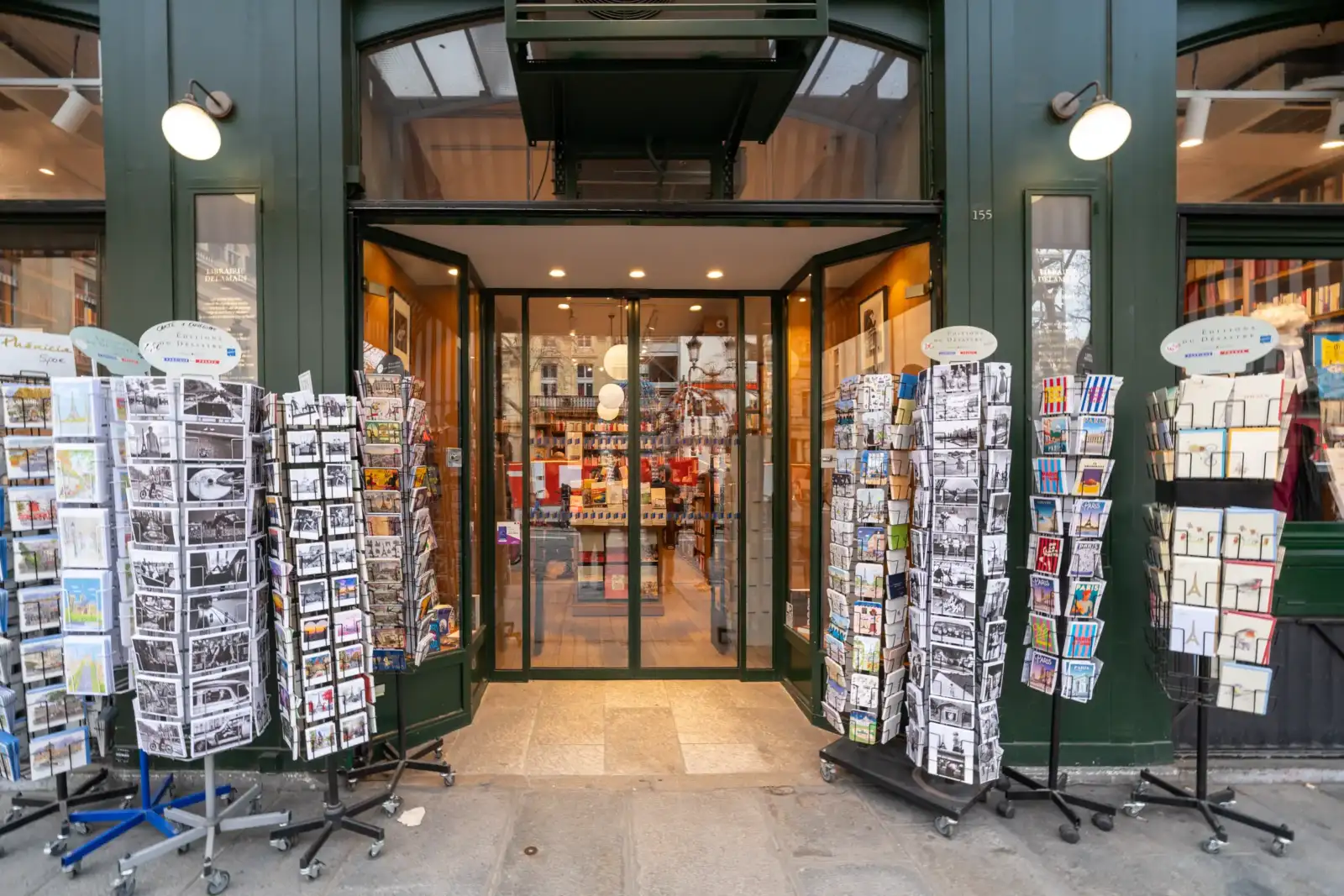 Façade verte de la librairie Delamain à Paris avec des présentoirs de cartes postales.